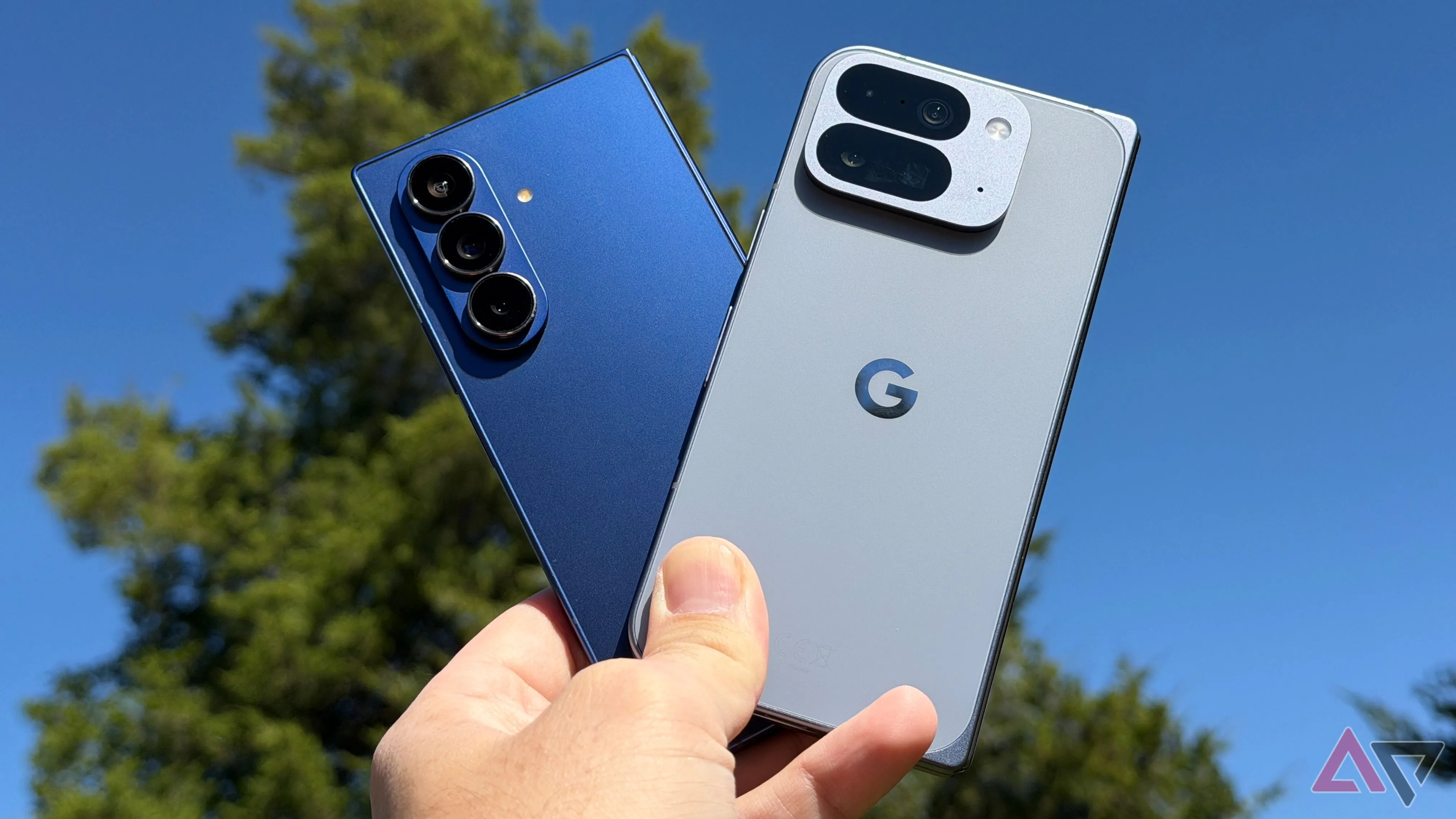 Hai chiếc Google Pixel 10 Pro Fold và Samsung Galaxy Z Fold 7 giơ lên nền trời, nhấn mạnh thiết kế mỏng nhẹ và màn hình lớn