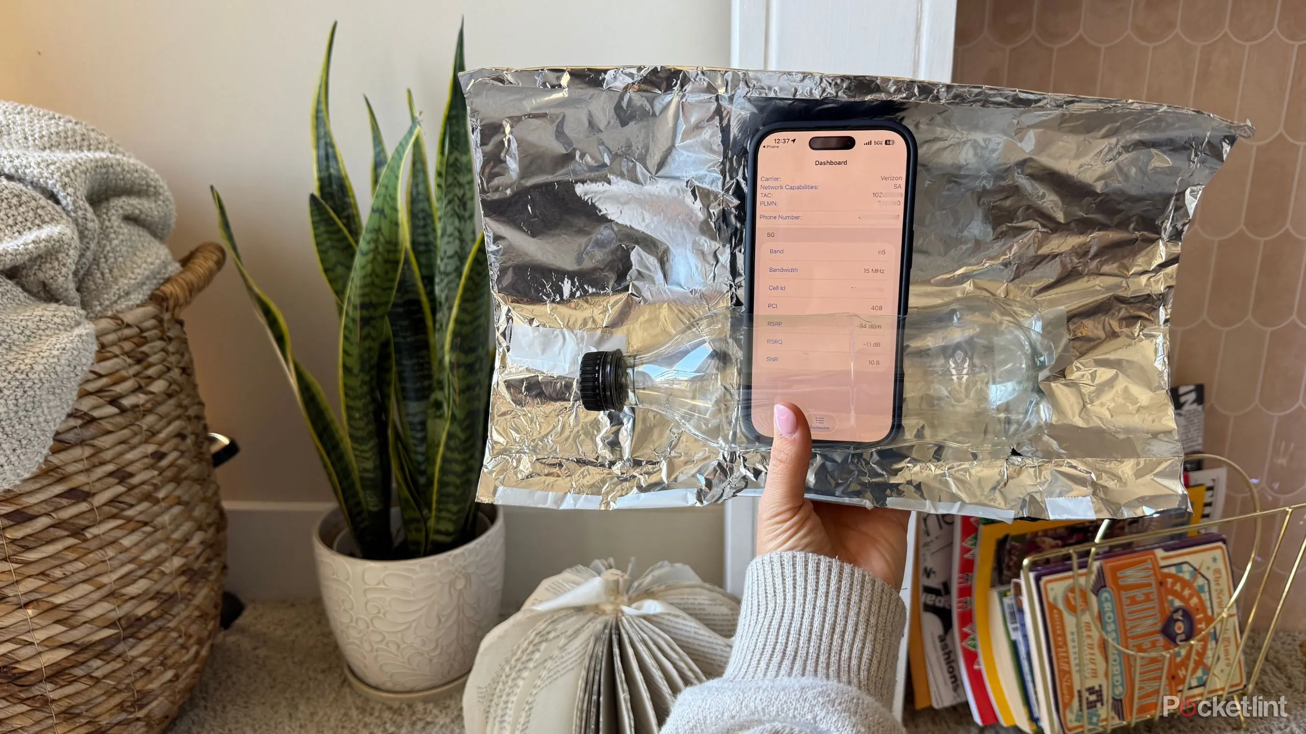 Hình minh họa bộ khuếch đại giấy bạc đặt cạnh iPhone, biểu trưng cho giải pháp tạm thời.