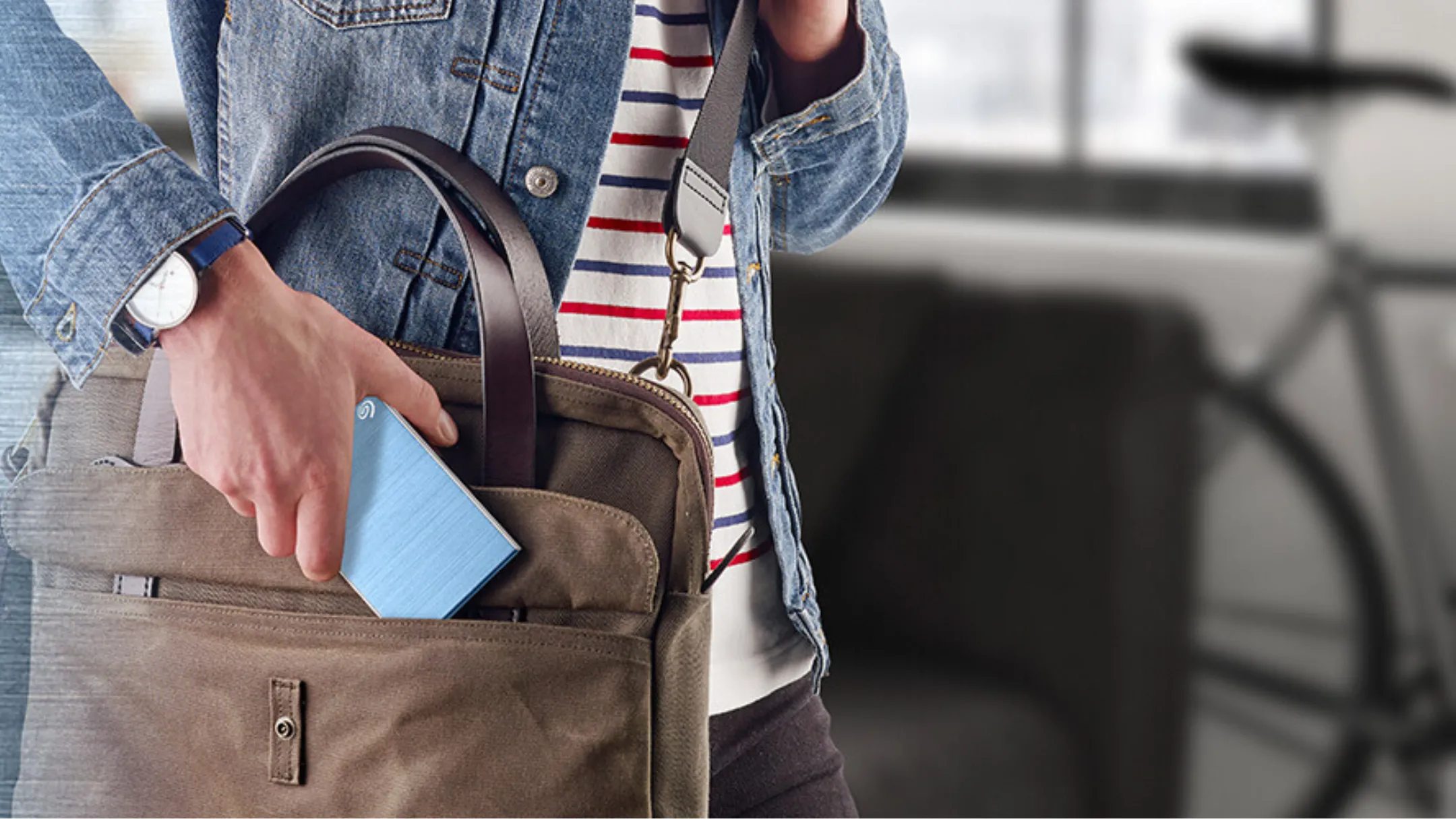 Người cầm ổ cứng di động Seagate Backup Plus Slim 2TB bên trong túi, minh họa lưu trữ game khi di chuyển