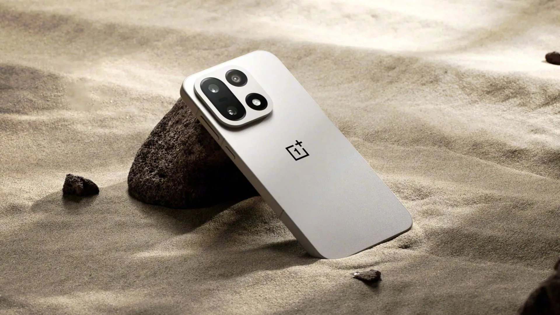 OnePlus 15 đặt trên nền cát, thể hiện thiết kế và ý niệm pin lớn cho trải nghiệm di động dài hơn.