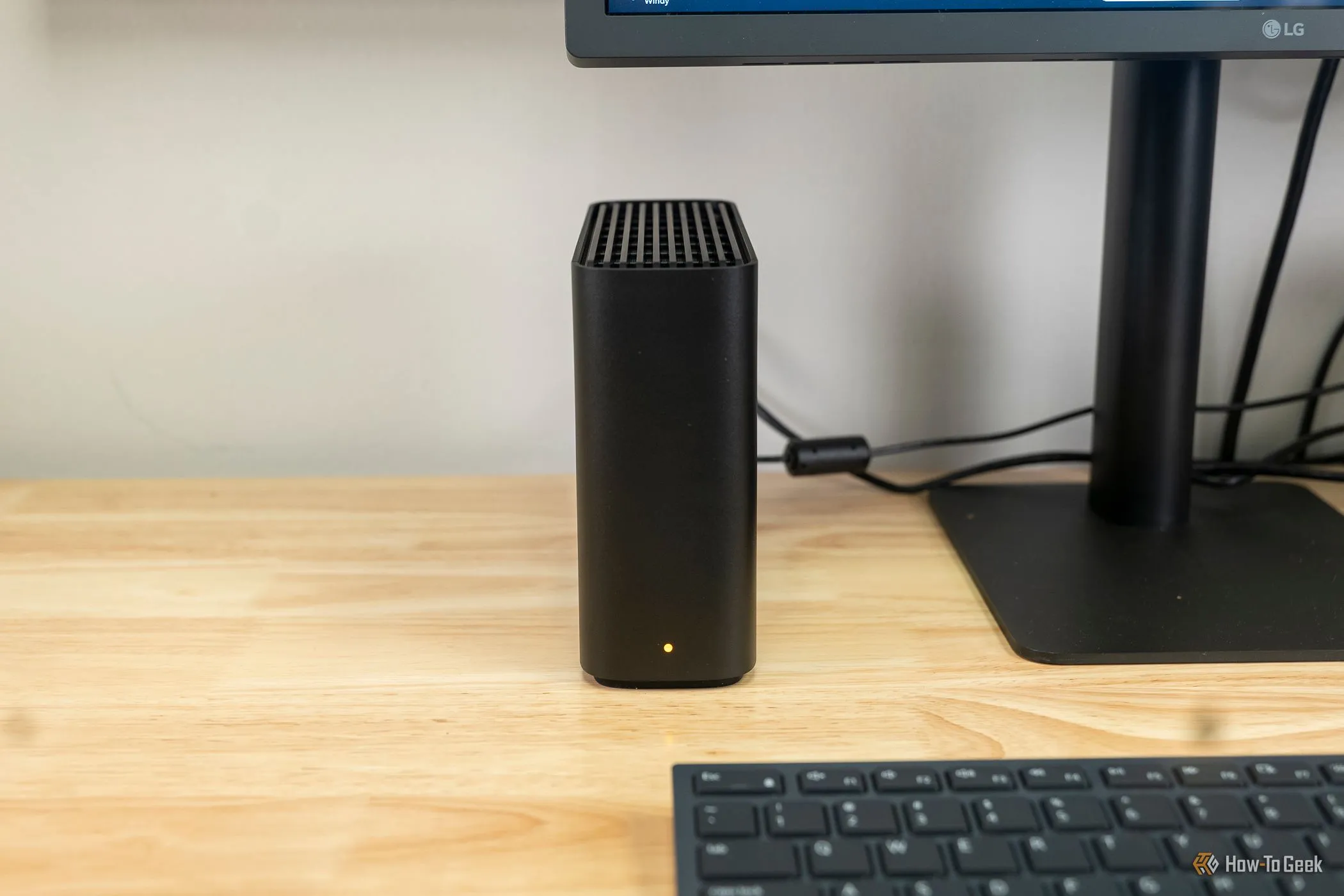 Synology BeeStation đặt cạnh màn hình máy tính, minh họa thiết bị NAS dùng cho Synology Photos và sao lưu ảnh tại gia.